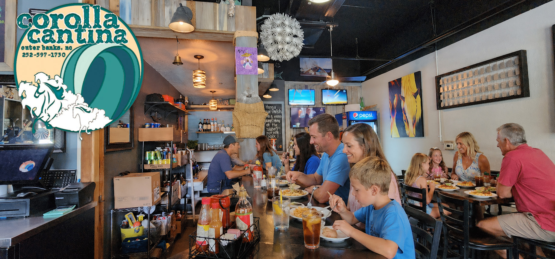 Families enjoying food and drinks at the bar and tables inside Corolla Cantina restaurant in Corolla, North Carolina with a lively, casual dining atmosphere