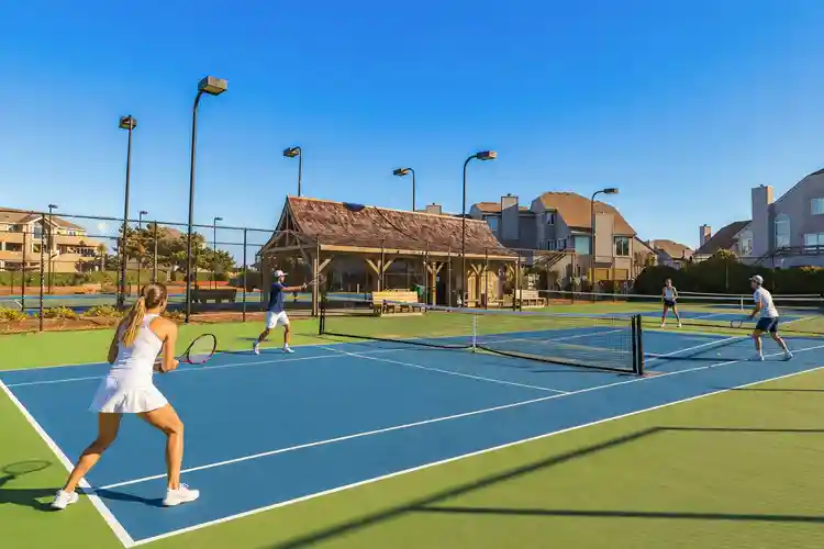 Family playing tennis on outdoor courts at Corolla Light Resort in the Outer Banks, North Carolina.