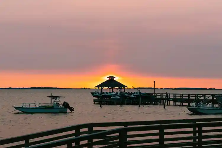 Sunset over the sound in Corolla NC with dock and boats