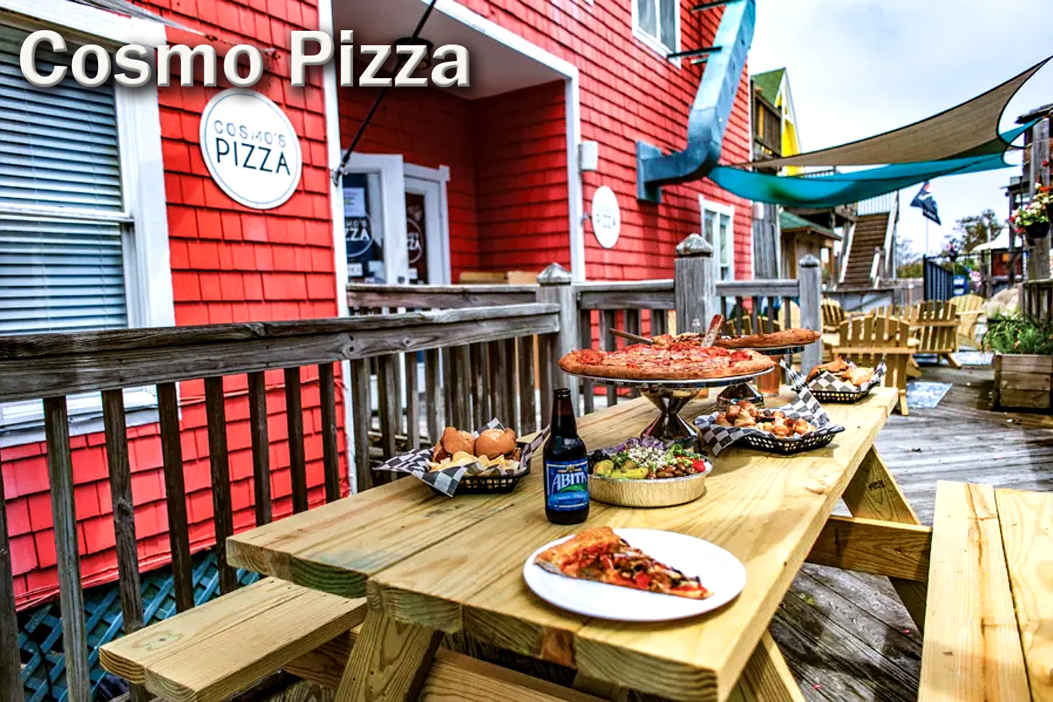 Outdoor dining at Cosmo’s Pizza in Corolla, North Carolina, featuring fresh pizzas, appetizers, and drinks on a wooden deck, a popular casual dining spot in the Outer Banks.