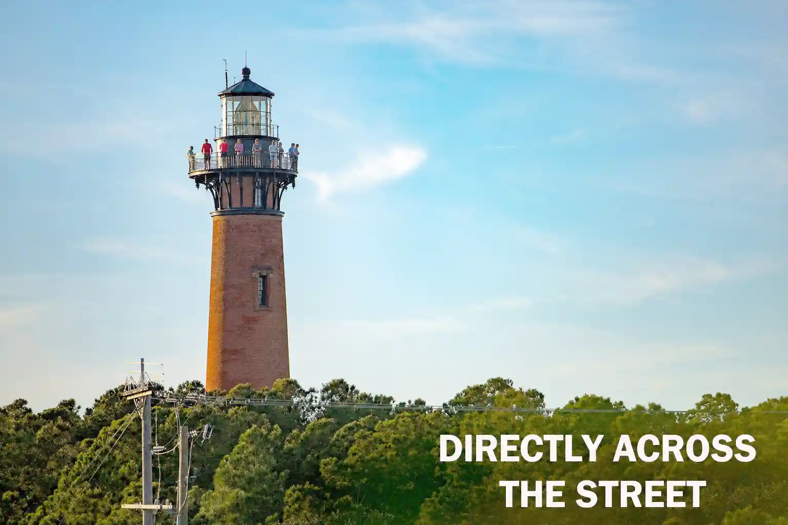 Currituck Beach Lighthouse in Corolla NC with visitors on the observation deck, located directly across the street from Beach Club at Whalehead vacation rentals in the Outer Banks