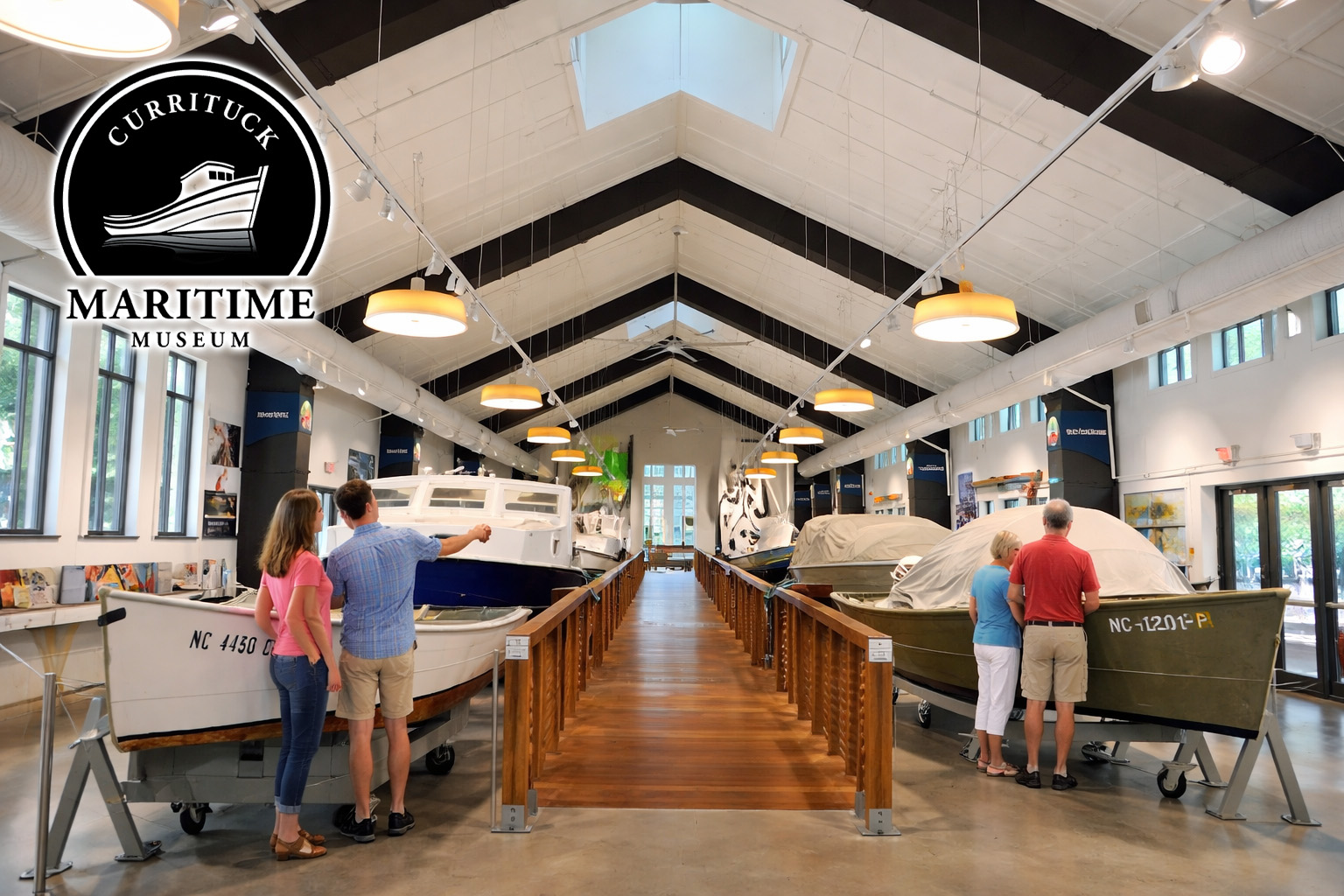 Visitors exploring boat exhibits inside the Currituck Maritime Museum in Historic Corolla Park, Outer Banks North Carolina