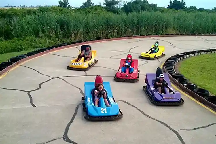 Kids and families racing colorful go-karts on the track at Full Throttle Speedway in the Outer Banks, North Carolina.