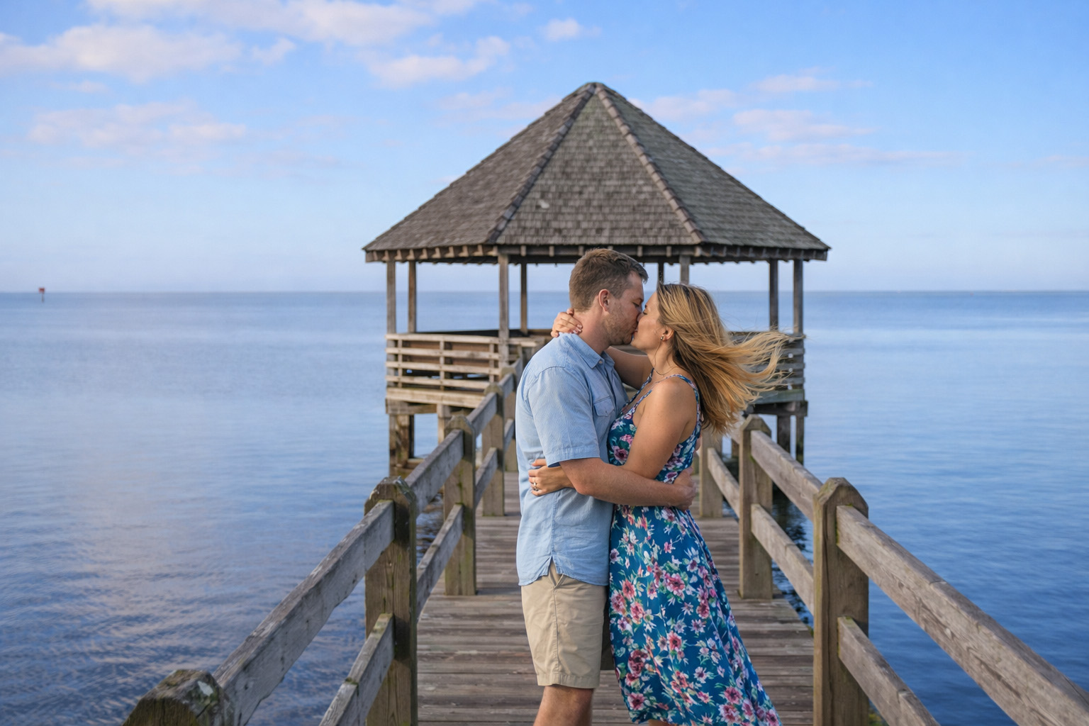 Couple embracing on the soundside gazebo dock in Historic Corolla Park, Outer Banks NC, overlooking calm coastal waters and scenic views