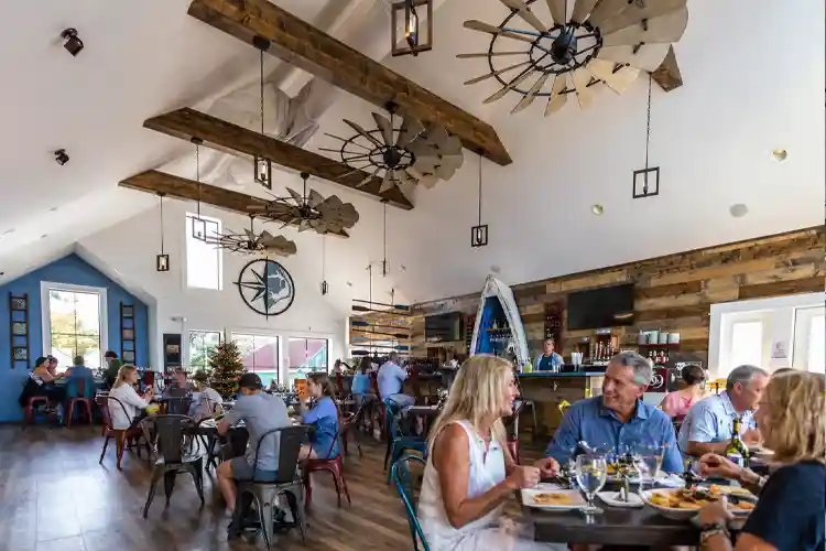 Guests enjoying dinner inside NC Coast restaurant in Duck, North Carolina, featuring a bright coastal interior, wood accents, and a lively dining atmosphere in the Outer Banks.