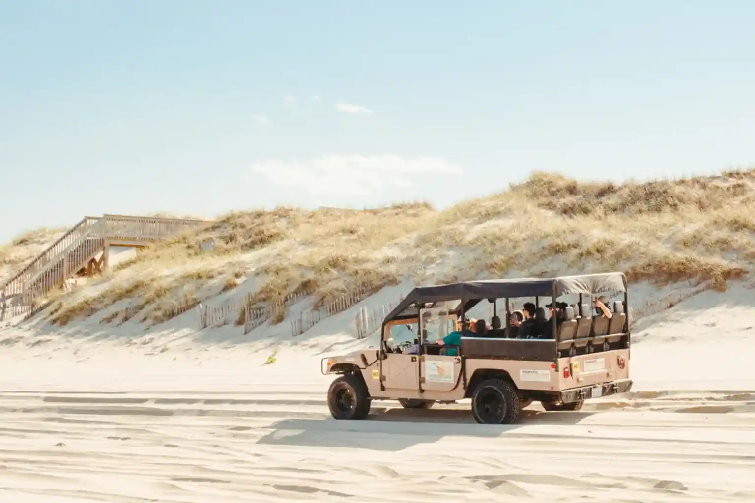 Open-air tour vehicle driving along the sandy Outer Banks beach near the Corolla dunes
