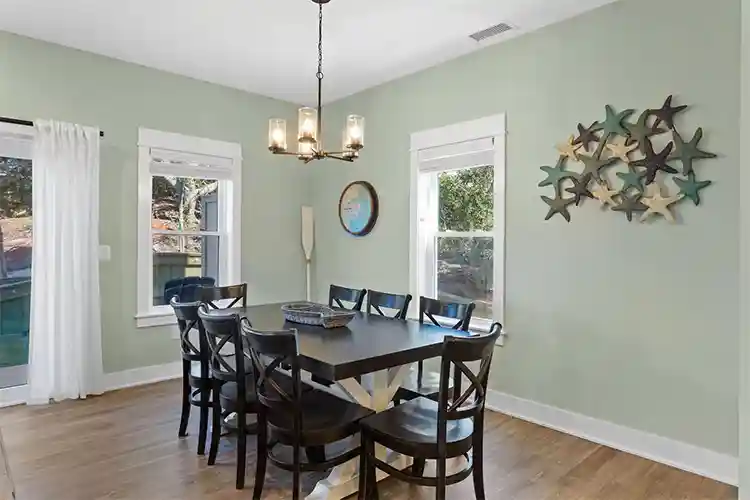Dining room at Sonoma's Hideaway in Corolla NC with coastal decor, large table seating, natural light, and access to outdoor deck