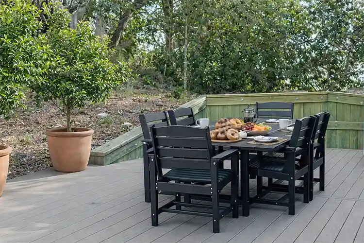 Outdoor deck at Sonoma's Hideaway in Corolla NC with dining table, breakfast spread, coffee, and private wooded setting