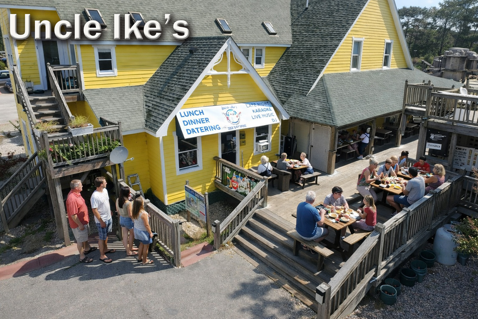 Uncle Ike’s Restaurant in Corolla, North Carolina, featuring a bright yellow coastal building with outdoor deck seating, families dining, and guests waiting to enjoy a popular Outer Banks dining spot.