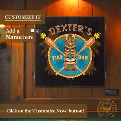 Custom name Tiki Bar dartboard cabinet mounted on wood-paneled wall with “Customize It – Add a Name Here” text overlay for personalized home bar decor.