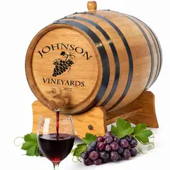 Personalized vineyard grapes engraved mini oak aging barrel with wine pouring into glass.