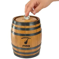 Close up of hand placing a coin into the slot of a mini oak barrel whiskey fund piggy bank