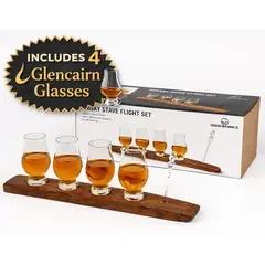 Handcrafted whisky stave flight set featuring four Glencairn glasses on a reclaimed bourbon barrel stave with “Includes 4 Glencairn Glasses” callout, premium whiskey tasting gift set with retail packaging displayed in background.