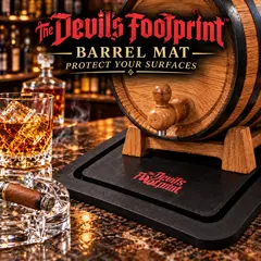 The Devil’s Footprint™ barrel mat protecting a bar surface beneath an oak aging barrel, shown with a whiskey glass and cigar.