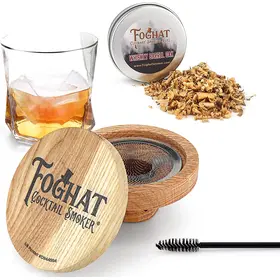 Foghat Cocktail Smoker lid positioned next to bourbon glass and oak smoking chips for product display.