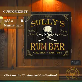 Custom Sully’s Rum Bar dartboard cabinet mounted on a wood-paneled wall, showing pirate skull and crossbones artwork with personalized name text for a home bar or game room.
