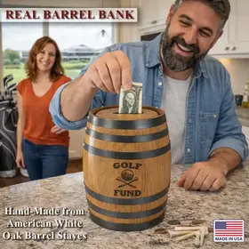 Handmade American White Oak barrel piggy bank with engraved Golf Fund design as a man deposits money while a woman smiles in a kitchen with golf course view.
