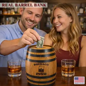 Couple placing money into bourbon fund oak barrel piggy bank while enjoying whiskey drinks