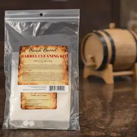 Swish Barrel cleaning kit displayed on a countertop with a small oak aging barrel in the background, designed for cleaning and maintaining whiskey barrels.