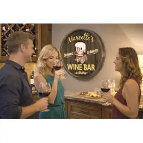 Barrel head wine bar sign displayed in home wine bar setting with guests enjoying wine