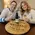 Couple enjoying wine at a table featuring a personalized engraved wine barrel head tray reading Amy & Bryan Weisberg with Jewish wedding inscription.