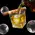 Bourbon being poured into whiskey glass with cigar rest and ice sphere on black background.
