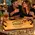 Couple enjoying whiskey at home with a personalized oak barrel head serving tray featuring custom engraving, wrought iron handles, and whiskey glasses.