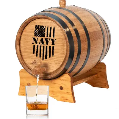 Navy engraved mini oak aging barrel with black steel hoops pouring whiskey into glass on wooden stand.