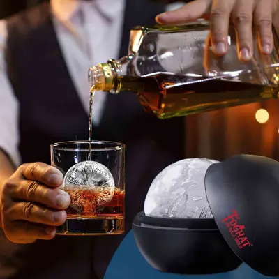 Whiskey being poured over a crystal-clear ice ball made with the Foghat ice sphere mold