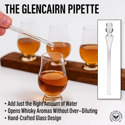 Hand using Glencairn pipette to add water to whisky in a Glencairn glass, with additional glasses on a whisky stave flight board.