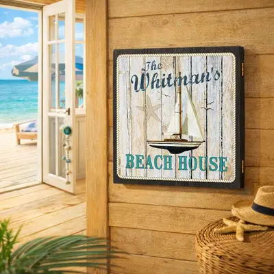 Closed beach house dartboard cabinet mounted on a coastal wood wall with ocean view through open doors, featuring nautical sailboat design and personalized beach house decor.