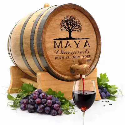 Personalized mini oak wine aging barrel with classic vineyard engraving pouring red wine into glass surrounded by fresh grapes.