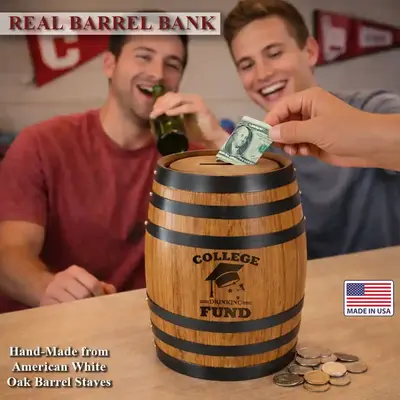 Two college students laughing behind a College Drinking Fund oak barrel piggy bank while one deposits money and the other drinks a beer.