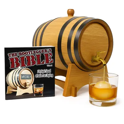 Oak whiskey aging barrel with brass spigot pouring bourbon next to Bootlegger’s Bible home aging kit