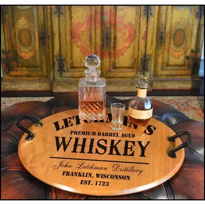 Authentic oak barrel head serving tray with wrought iron handles displaying whiskey decanter and glasses on a rustic bar setup.