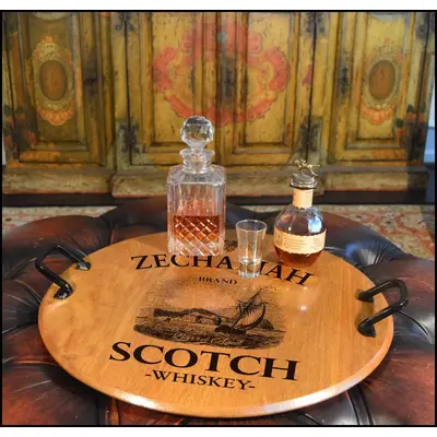 21-inch authentic oak barrel head serving tray with wrought iron handles displaying whiskey decanter and glasses in a rustic bar setting.