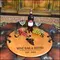 'Grapes' Barrel Head Serving Tray 21-inch round reclaimed oak barrel head serving tray with wrought iron handles displaying wine bottle, glasses, and grapes in a rustic wine bar setting.