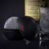 Foghat ice ball mold creating a large whiskey ice sphere beside a glass of bourbon