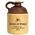 Vintage-style ceramic moonshine jug with brown top and beige body featuring skull-and-crossbones graphic and humorous text reading ‘Women or Whiskey, hard to say which will kill you first.’ Rustic collectible whiskey jug with cork stopper