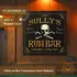 Custom Sully’s Rum Bar dartboard cabinet mounted on a wood-paneled wall, showing pirate skull and crossbones artwork with personalized name text for a home bar or game room.