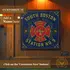 Fire Dept dartboard cabinet mounted on wood wall with “Add a Name” personalization option, blue fire station design and gold detailing.