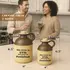 Two ceramic moonshine jugs in half-gallon and 1-liter sizes with brown tops and humorous text ‘The liver is evil and must be punished,’ displayed on a kitchen counter with people holding drinks in the background; novelty drinkware and rustic barware collectibles.