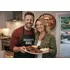 Couple holding BBQ platter in kitchen with personalized barrel end barbecue sign on wall