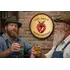 Handmade White Lightning whiskey barrel head wall decor featured in man cave setting with two men raising glasses of bourbon.