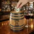 Mini oak barrel piggy bank engraved with Wine Fund logo on wine bar counter with red wine glass and dollar bill being inserted