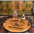 'Darwin Bros.' 21-inch round authentic oak barrel head serving tray with wrought iron handles displaying bourbon decanter and glasses in a rustic bar setting.